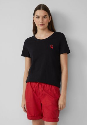 T-shirt en coton noir à manches courtes et décolleté rond, avec un petit motif rouge brodé. Assorti à un short rouge, taille froncée.