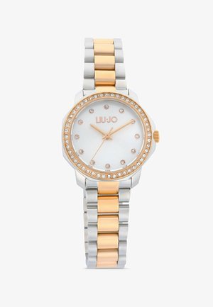 Montre ronde en métal bicolore avec index en cristal et lunette, cadran blanc, aiguilles en or rose, et bracelet articulé en argent et or rose.