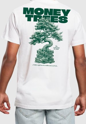 T-shirt en coton blanc arborant une illustration verte d'un arbre poussant à partir de piles d'argent. Le texte indique "MONEY TREES" en lettres vertes épaisses.
