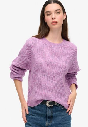 Jasnofioletowy sweter z dzianiny o fakturowanym wzorze, okrągłym dekolcie i oversize'owych rękawach, w połączeniu z jeasami o wysokim stanie i paskiem.