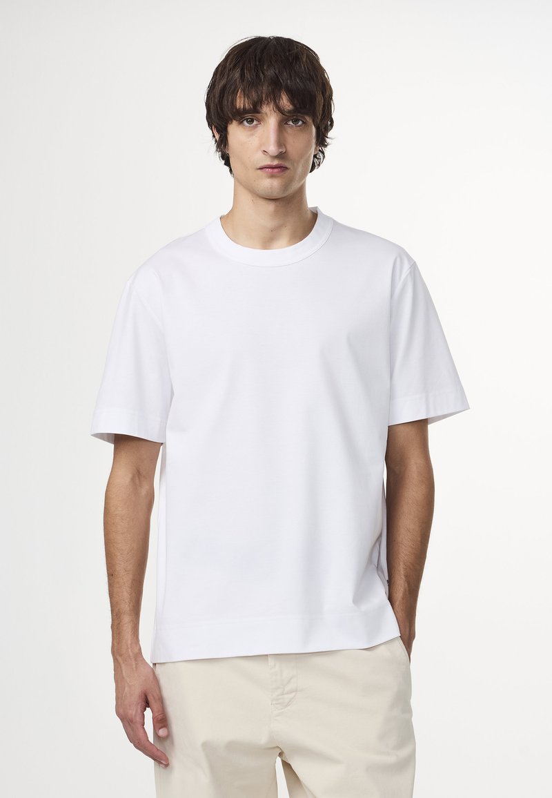 Witte t-shirt met korte mouwen en ronde hals, gemaakt van een gladde stof. Heeft een rechte zoom en een ontspannen pasvorm. Draagt met lichte broek.
