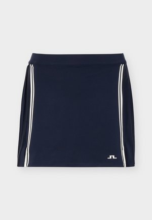 Jupe de sport bleu marine avec des rayures blanches verticales sur les côtés et un petit logo blanc sur la partie inférieure droite à l'avant.