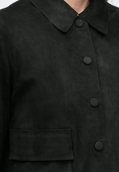 Μαύρο μπουφάν από σουέντ με κλασικό γιακά, κλείσιμο με κουμπιά μπροστά και τσέπη πατσέτα στην αριστερή πλευρά για επιπλέον λεπτομέρεια.