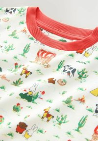 T-shirt en coton blanc avec col en ribcord rouge, présentant un motif multicolore d'animaux amusants et de cactus sur le tissu.