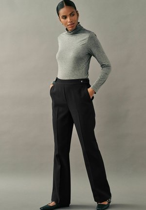 Šedý dlouhý rukáv rolák, který je kombinován s černými kalhotami s vysokým pasem, jež mají přední kapsy a knoflíkové detaily. Slim-fit střih.