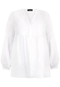 Biała lniana bluzka z dekoltem w serek, marszczonym gorsem i długimi bufkami. Miękka faktura o subtelnej przezroczystości. Bez widocznych wzorów.