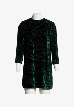 Robe courte en velours avec motif zébré vert foncé et noir et manches trois-quarts sur un mannequin blanc.