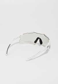 Sonnenbrille mit einem weißen Rahmen, leichtem Design, gebogenen Gläsern und schwarzen Gumminasenpads, mit einer eleganten Form und minimalistischen Akzenten.