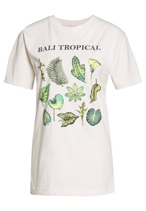 Heled beige puuvillane T-särk, millel on erinevate roheliste lehtede botaaniline print, ülal disaini kohal on must tekst "BALI TROPICAL".