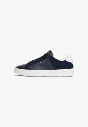 Sapatilhas de homem de cano baixo em pele azul-marinho e camurça, com sola de borracha branca, atacadores e logótipo da Tommy Hilfiger na lateral.
