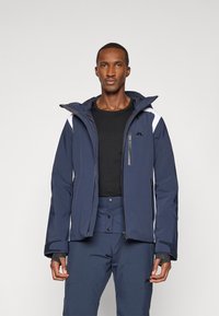 Tengerészkék, szigetelt kabát fehér díszítéssel, cipzáros zsebekkel és állítható mandzsettával. Vízálló anyag, kapucnis kialakítás és modern fazon.