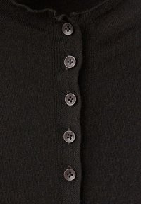 Gros plan d'un tissu tricoté noir avec cinq boutons noirs espacés uniformément cousus verticalement au centre.