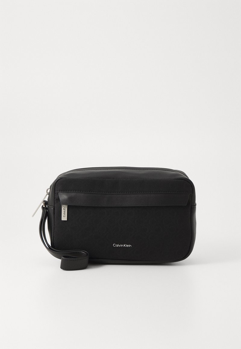 Bolsa retangular preta feita de material sintético, com frente texturizada, parte superior lisa, uma alça destacável e detalhe do logótipo Calvin Klein.
