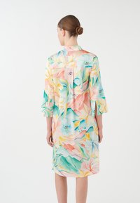 Robe à motif floral en tissu doux, comprenant des couleurs pastel comme le rose, le jaune et le vert. Manches trois-quarts et détail de col.
