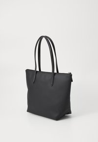 Sac cabas noir en matériau synthétique texturé avec deux longues poignées et une fermeture éclair en haut. Forme plate sans ornements.