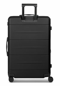 Valigia rigida nera con superficie testurizzata, manico telescopico, maniglia laterale e quattro ruote multidirezionali lisce.