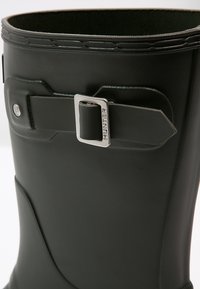 Grüner Gummiregenstiefel mit strukturiertem Finish, verstellbarem Riemen mit silberner Schnalle und runder Knöchelgestaltung für Komfort.