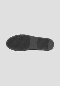 Semelle de chaussure en caoutchouc noir avec des motifs texturés, une zone centrale lisse et des crêtes surélevées pour une meilleure adhérence et traction.