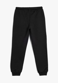 Pantalones de chándal negros hechos de una tela suave, con una cintura elástica y puños, que presentan una textura lisa y un diseño ajustado y estilizado.