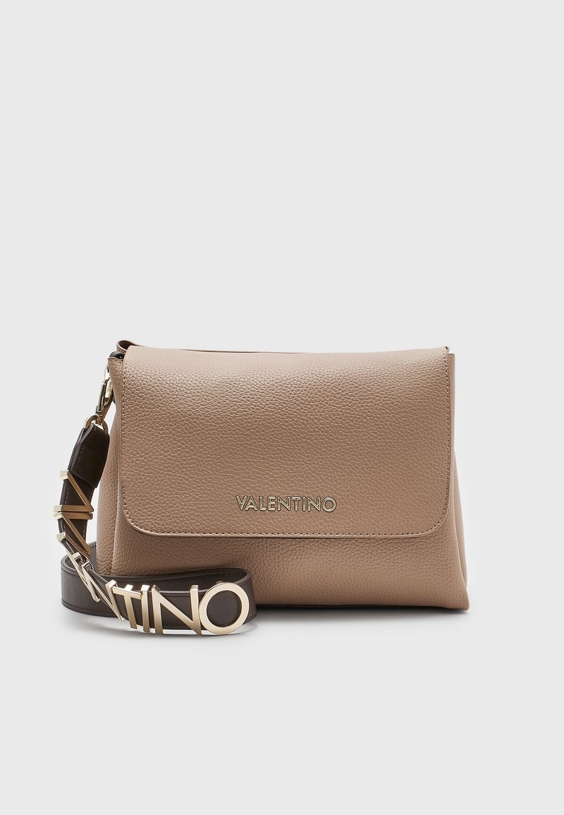 Beige läder crossbody-väska med en vikbar klaff, logotyp i guldton och en mörkbrun rem med guldaccenter. Slät textur med en strukturerad form.