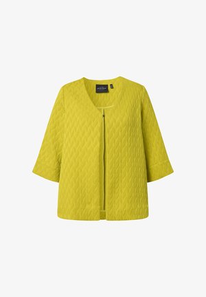 Keltainen teksturoidusta neuloksesta valmistettu takki, jossa on kolme neljäsosahihnaa ja vetoketjusuljenta edessä, esitetty valkoisella taustalla.