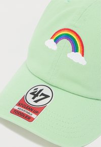 Πράσινο ρυθμιζόμενο καπέλο με κεντητό ουράνιο τόξο και σύννεφα στο μπροστινό μέρος. Περιλαμβάνει ετικέτα με λογότυπο και πληροφορίες μεγέθους.