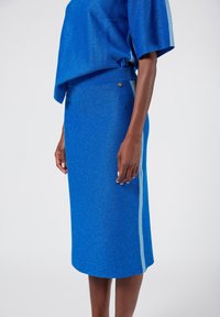 Blue knitted top and skirt set with a textured finish, featuring a relaxed fit, ribbed waistband, and subtle light blue side stripes.