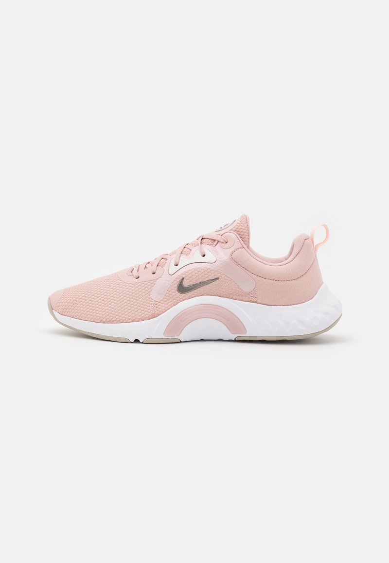 Scarpa da corsa Nike rosa chiaro con tomaia in rete, suola bianca ammortizzata, logo Swoosh grigio e linguetta sul tallone vista dal lato esterno.