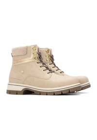 Botas de tobillo impermeables beige con material de ante, herrajes dorados y cordones marrones. La suela de goma gruesa ofrece tracción y estabilidad.