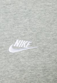 Il tessuto di cotone grigio presenta una sottile texture con un logo Nike ricamato in bianco nell'angolo in basso a destra.