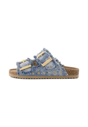 Sandale à enfiler en denim avec deux brides réglables à boucles, bords effilochés, clous dorés, et semelle intérieure en liège avec semelle extérieure en caoutchouc texturé.