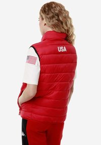 Gilet rosso con collo alto. "USA" stampato sul retro. Presenta tasche laterali e accenti neri sulle spalle. Texture morbida e trapuntata.