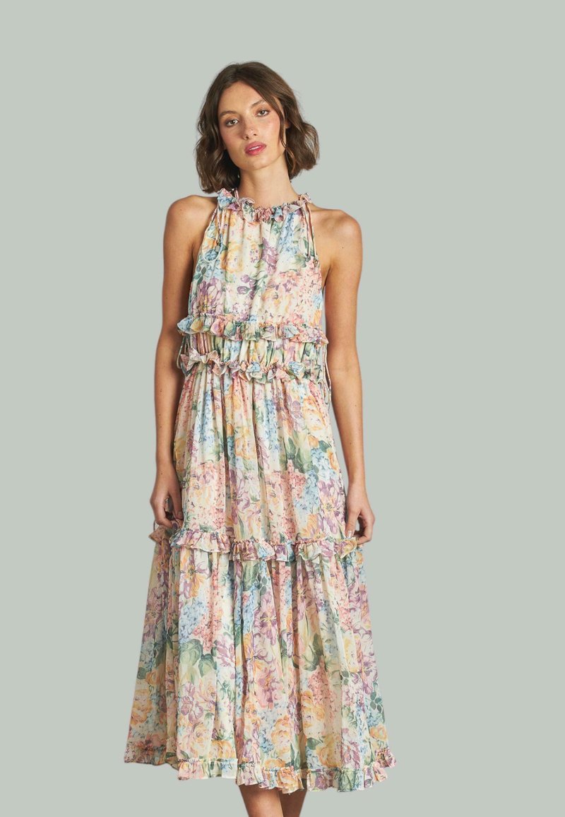 Abito lungo floreale con colori pastello, dettagli a rouches, scollatura a halter e gonna a strati. Realizzato in tessuto leggero e fluido.