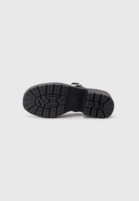 Black rubber boot sole with a textured grip pattern, featuring a smooth toe and a sturdy heel for traction and durability.