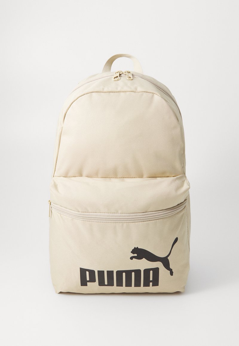 Bežový látkový batoh s guľatým vrcholom, predným vreckom na zips a výrazným čiernym logom "PUMA". Má dvojité zipsy a nosnú rukoväť.