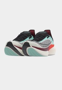 Ζευγάρ ι παπουτσιών τρεξίματος Saucony με μαύρα κορδόνια, επάνω μέρος από λευκό και μέντα πράσινο δίχτυ, κόκκινες λεπτομέρειες και παχιές μαξιλαρωμένες σόλες.