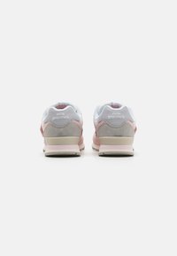 Des chaussures New Balance avec un mélange de matériaux en gris doux, rose et blanc ; elles présentent un col rembourré et des accents en suède texturé.