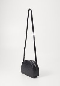 Bolso de hombro negro de piel sintética con textura de cocodrilo brillante, forma curvada, correa delgada y cierre con cremallera.
