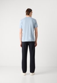 Tricou din bumbac de culoare albastru deschis, cu mâneci scurte, guler rotund, asortat cu pantaloni închisi. Design simplu, textură fină, croială confortabilă.
