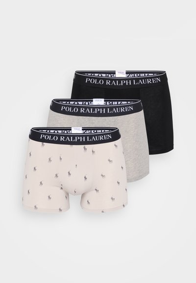 Três pares de boxers masculinos, apresentando um par bege com padrões de logótipos repetidos, um par cinza e um par preto sólido. Todos têm cinturas com a marca.