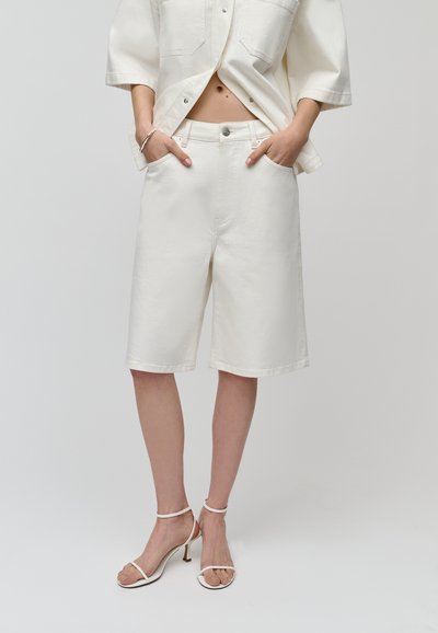 Shorts in denim bianco con vestibilità rilassata, dotati di tasche frontali e chiusura con bottone. Il materiale ha una texture liscia e un design minimale.