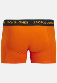 Boxer shorts de algodón naranja con una cinturilla negra que presenta el texto amarillo "JACK & JONES". Textura suave y diseño ajustado.