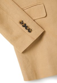 Helle beige Leinenjacke mit einem Ärmel, der vier dunkle, gemusterte Knöpfe und dezente Stickereien am Manschettenbereich aufweist. Detaillierte Tasche an der Jacke.