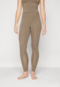 Brune tights med høy midje, laget av elastisk materiale. Glatt tekstur, tettsittende design og ankellang finish.