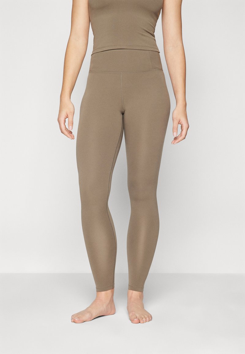 Brune tights med høy midje, laget av elastisk materiale. Glatt tekstur, tettsittende design og ankellang finish.