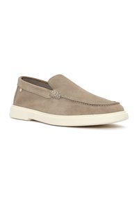 Beige suede slip-on shoe with a white rubber sole, featuring subtle stitching and a textured finish on the upper. No visible branding.