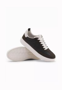 Sneakers i mörkbrun mocka och slät läder, med vita snören och en texturerad gummisula. Har en vadderad krage och dragflik.