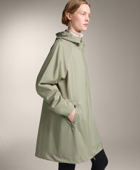 Impermeabil verde deschis, până la genunchi, cu glugă, fermoar frontal, buzunare pe laterale și o croială lejeră; fabricat dintr-un material neted, rezistent la apă.
