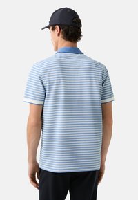 Gestreept poloshirt in lichtblauw met witte strepen, voorzien van een blauwe kraag en korte mouwen. Materiaal: katoenmix met een gladde textuur.