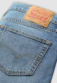 Vaqueros Levi's 511 con denim azul claro, costuras doradas contrastantes y una etiqueta clásica en el faldón trasero.